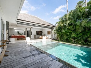 Een modern huis met een zwembad, terras en weelderige begroeiing.