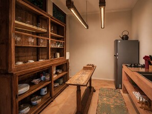 A kitchen with wooden cabinets, a wooden table, a refrigerator, and a kettle. - Stylish 3BR Mediterranean Sanctuary in Uluwatu (Pecatu)