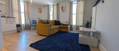 Una sala de estar moderna con un sofá, una mesa de centro y un televisor montado en la pared.