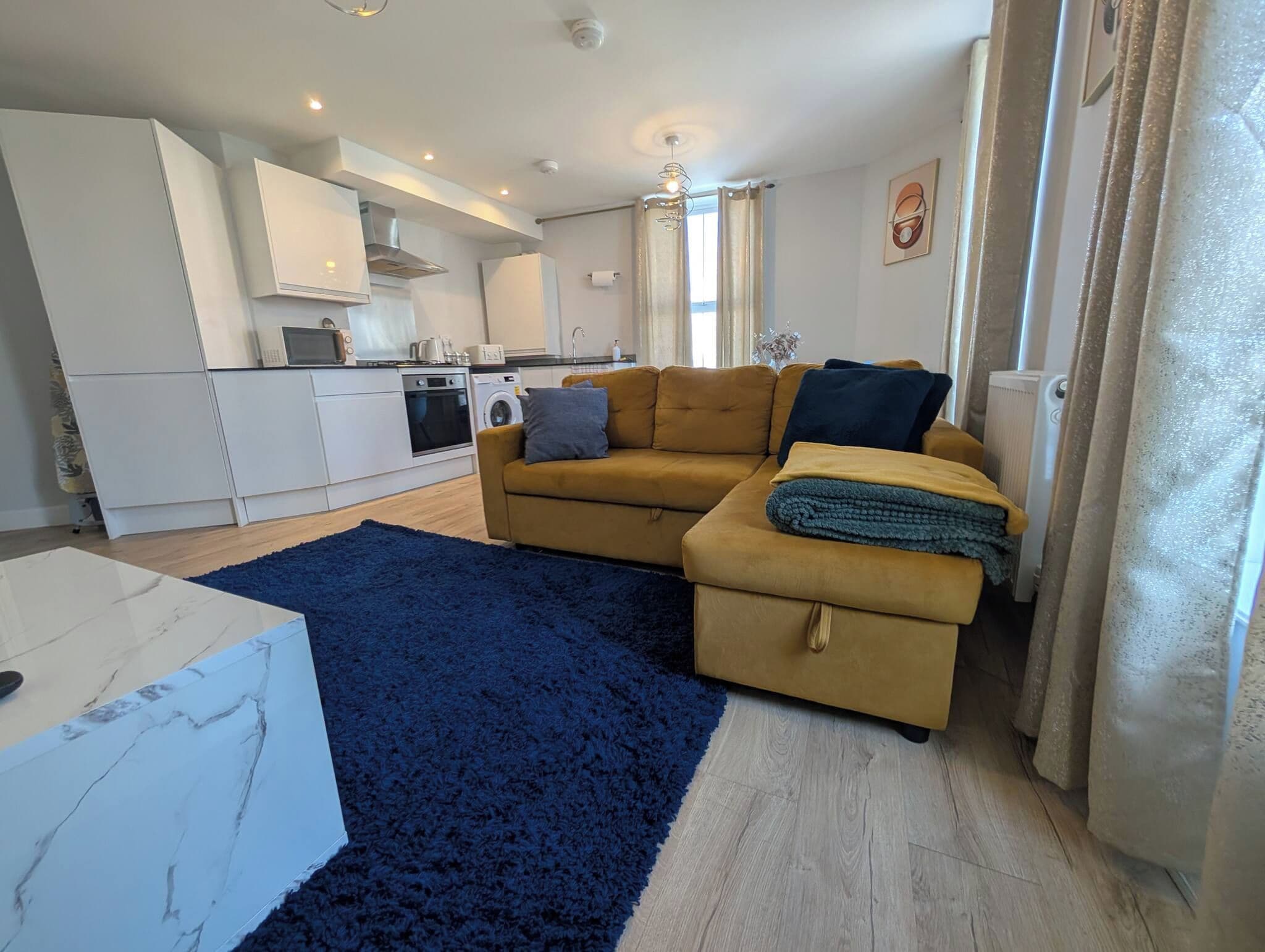 Ein gemütlicher Wohnbereich mit Sofa, Couchtisch und Küchenzeile.