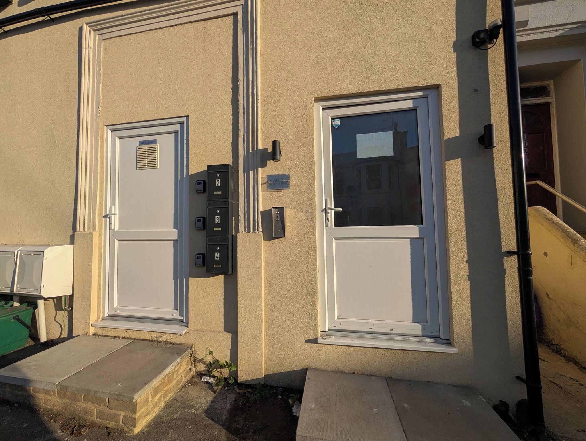A building facade with two doors, a mailbox, and a utility box.