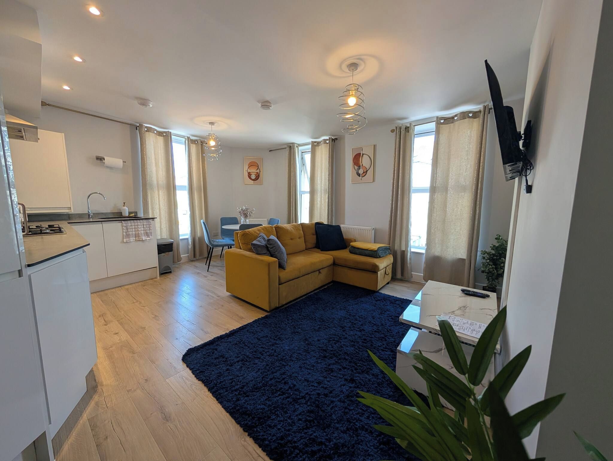 Ein modernes Wohnzimmer mit einer Couch, einem Couchtisch und einem an der Wand befestigten Fernseher.