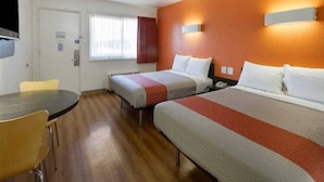 A hotel room with two beds, a desk, and a chair.