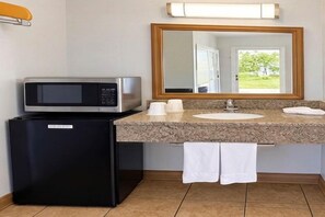 A bathroom with a microwave, refrigerator, sink, and a mirror reflecting a door and greenery outside. - 2 Queen Beds | Smoking (Claremont)