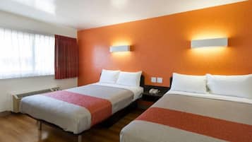 A hotel room with two beds, a window with curtains, a wall-mounted nightstand, and a thermostat.