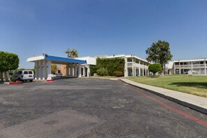 A parking lot with a gas station and a building with multiple floors and balconies.