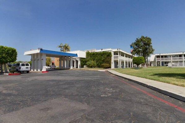 A parking lot with a gas station and a building with multiple floors and balconies. - 2 Queen Beds | Smoking (Claremont)