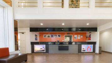 A hotel reception area with a counter, a bench, and a view of the upper floor.