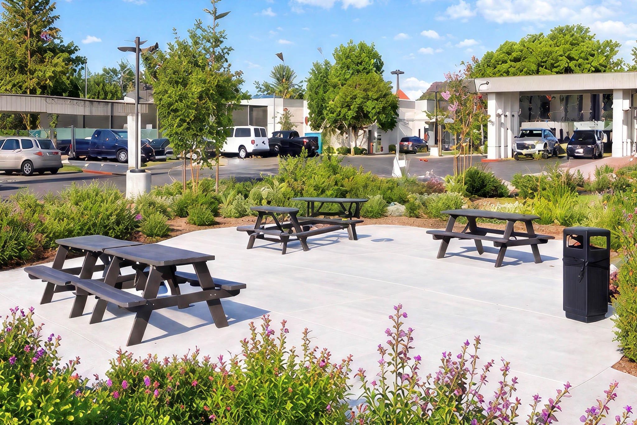 A parking area with picnic tables and a trash bin.