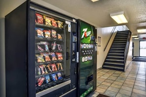 A vending machine with various snacks and a 7UP dispenser in a hallway with a staircase. - Spacious room, 2 double beds | Accessible/Bathtub (Saint Joseph)