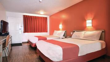 A hotel room with two beds, a desk, and a television.