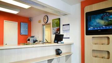 A reception area with a desk, computer, and a mounted television.