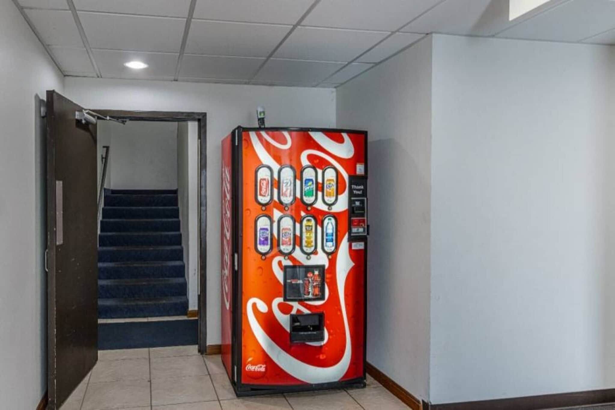 Ein Getränkeautomat mit verschiedenen Auswahlmöglichkeiten in einer Diele mit Treppe.