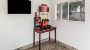 A room with a flat-screen TV mounted on the wall, a table with a coffee station, and a window with a view of trees. - 2Full Bed Non-Smoking|Jacksonville (Jacksonville)