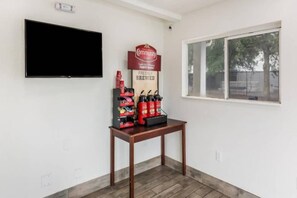 A room with a flat-screen TV mounted on the wall, a table with a coffee station, and a window with a view of trees. - 2Full Bed Non-Smoking|Jacksonville (Jacksonville)