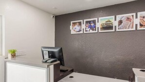 A reception desk with a computer, a small plant, and a wall with framed pictures. - 2Full Bed Non-Smoking|Jacksonville (Jacksonville)