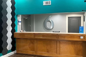 A reception desk with a large number '6' sign, a security camera, and a blue informational sign.