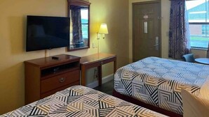 A hotel room with two beds, a TV, a desk, a lamp, and a door. - 2 Queen Beds|Smoking,Micfridge (Morrilton)