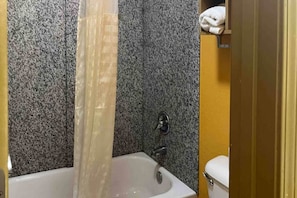 Um banheiro com banheira, cortina de chuveiro e vaso sanitário.