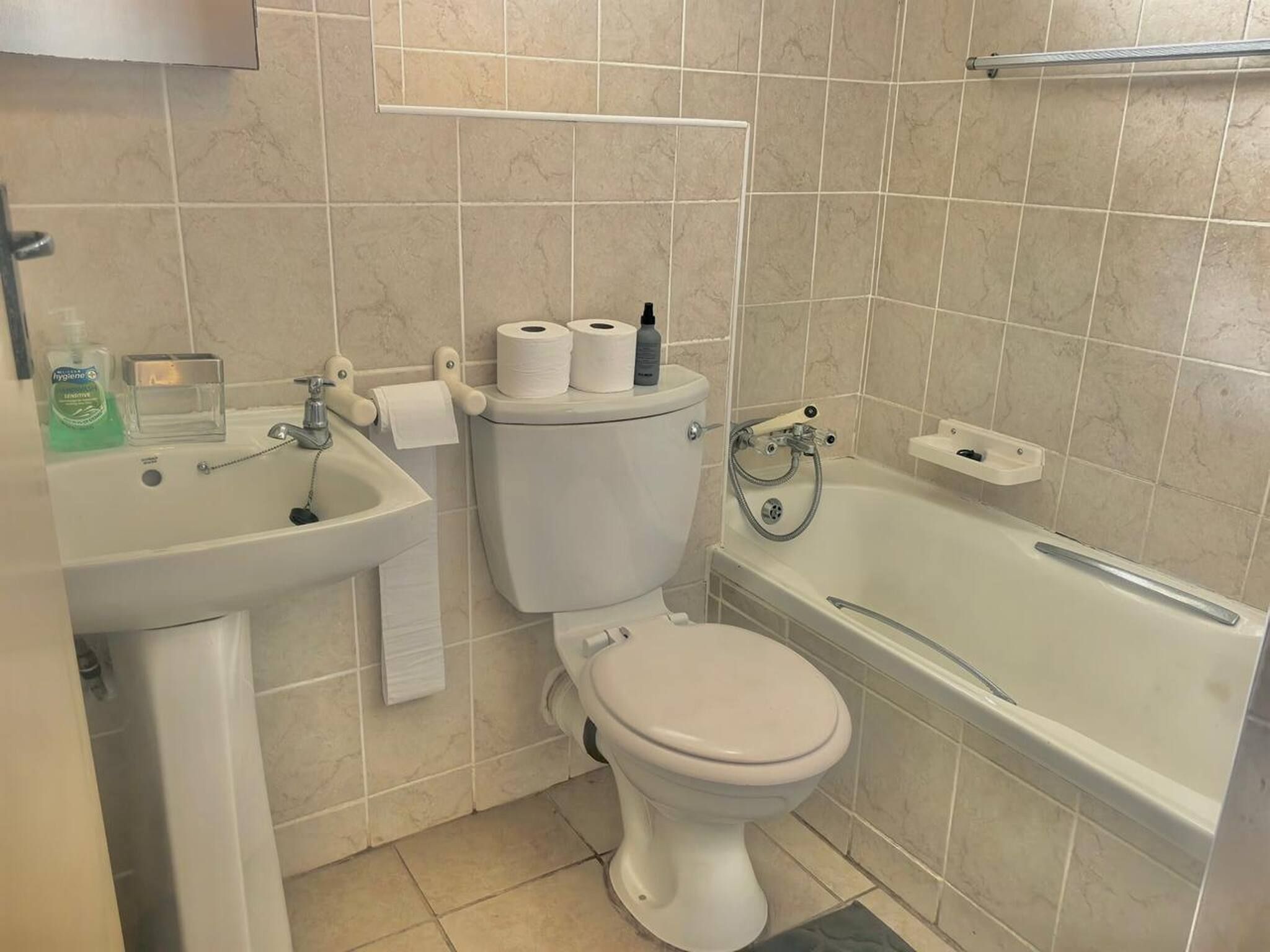 Een badkamer met toilet, wastafel en bad.