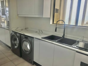 Een wasruimte met een wasmachine, een spoelbak en kastjes.