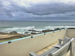 A balcony with a view of the ocean and rocky shoreline. - 10 C-Front Penthouse (Margate)