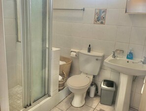 Un bany amb plat de dutxa de vidre, vàter, bidet i un lavabo.