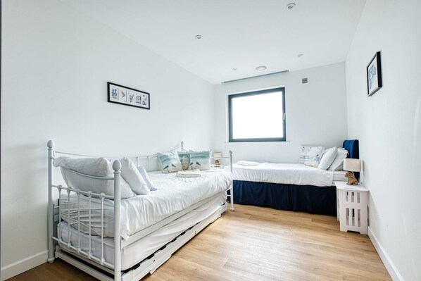 Een slaapkamer met een bed, een eenpersoonsbed, een raam en een wandplank.