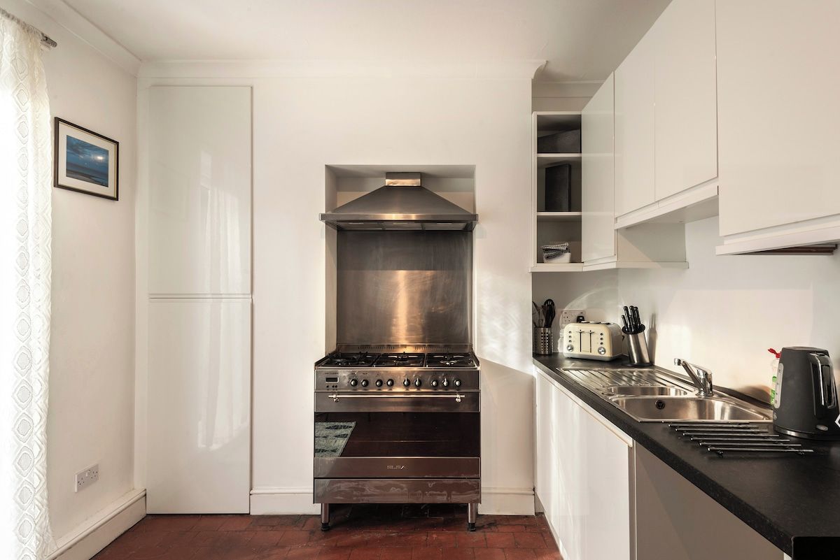 A compact kitchen with a stainless steel stove, a toaster, and a sink.