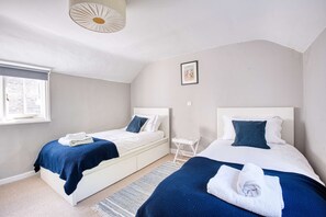 A bedroom with two beds, a window, a small table, and a picture on the wall. - Longley Cottage | Ramsgate Seaside Charm | Quiet (Ramsgate)