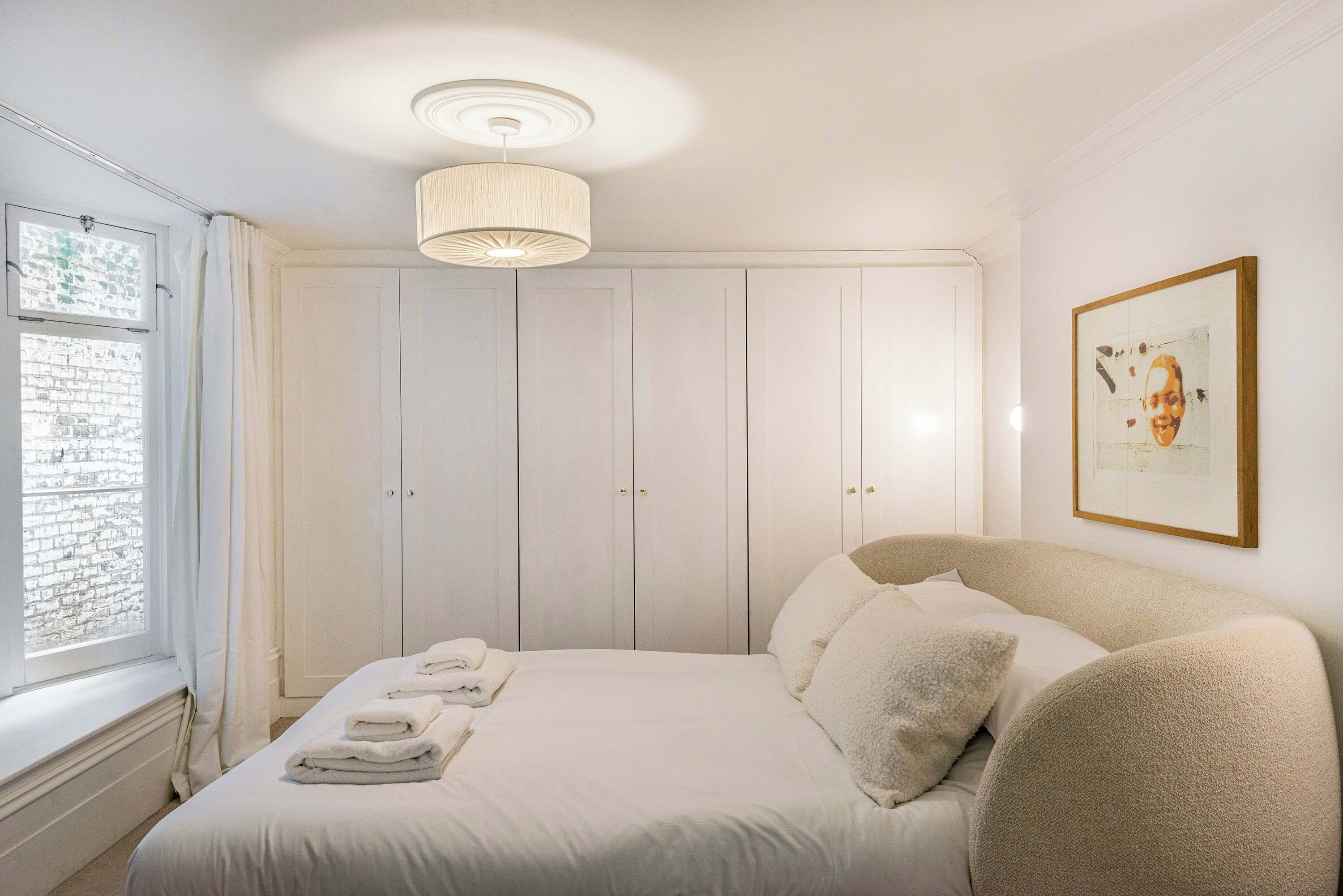 Ein Schlafzimmer mit einem Bett, einem Fenster, einem Kleiderschrank und einer Deckenleuchte.