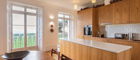 Cocina moderna con armarios de madera, una isla central y un comedor con mesa y sillas.