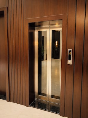 Un ascensor moderno con pantalla digital, puerta de cristal y diseño de panel de madera.