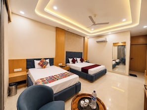 A hotel room with two beds, a ceiling fan, an air conditioning unit, and a mirror reflecting the room.