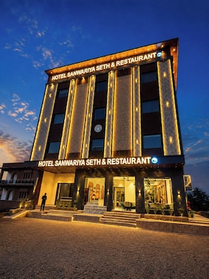 Un hotel con fachada moderna, señalización iluminada y una entrada bien iluminada.