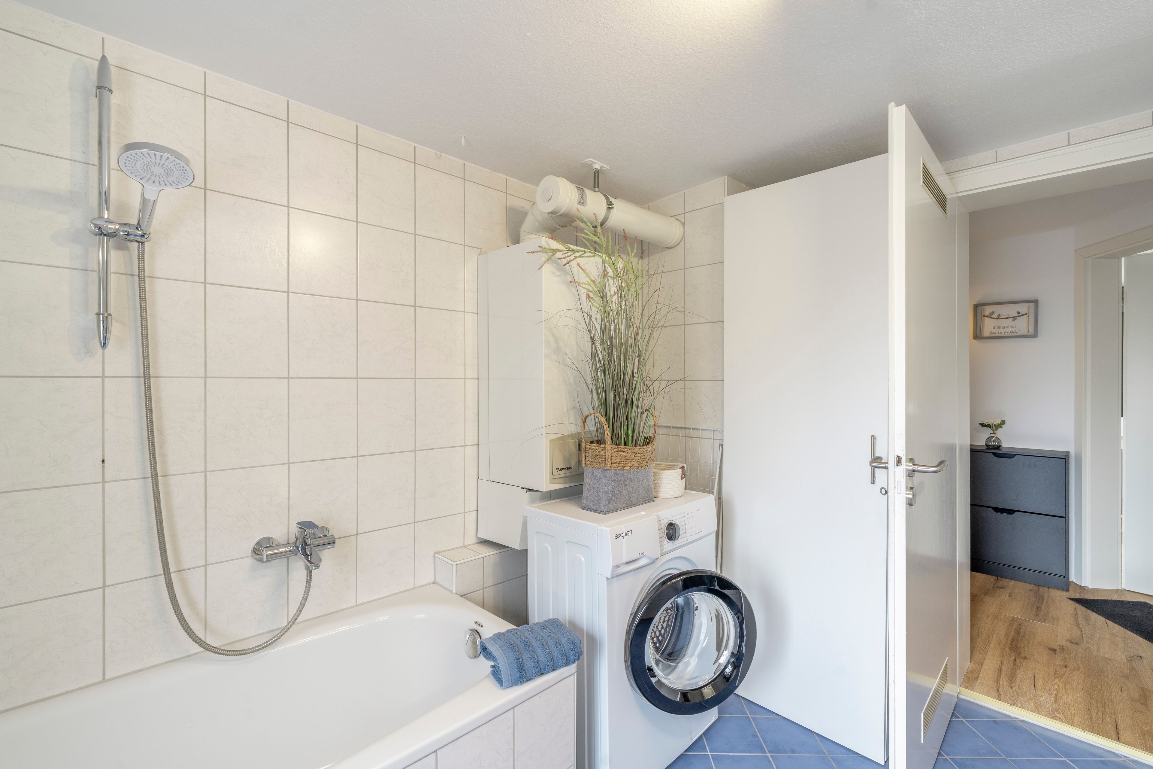 Ein modernes Badezimmer mit einer Badewanne, einer Dusche und einer integrierten Waschmaschine.