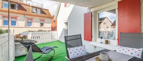 Un balcone con un tavolo apparecchiato per mangiare, sedie e un elemento decorativo al centro.