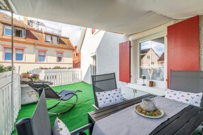 En balkon med et spisebord, stole og en dekorativ midtpunkt.