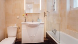 A bathroom with a toilet, sink, mirror, and glass-enclosed shower. - Luxury 1BR steps away from Champs Elysees (Paris)