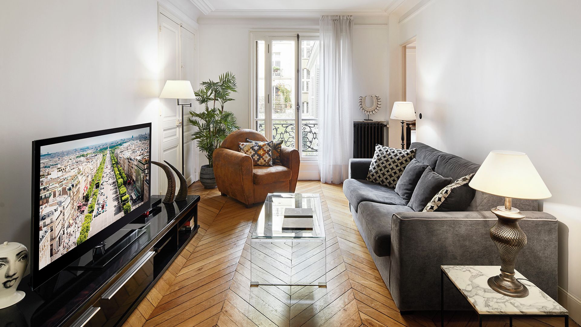 Een moderne woonkamer met een televisie, bank, fauteuil en salontafel.