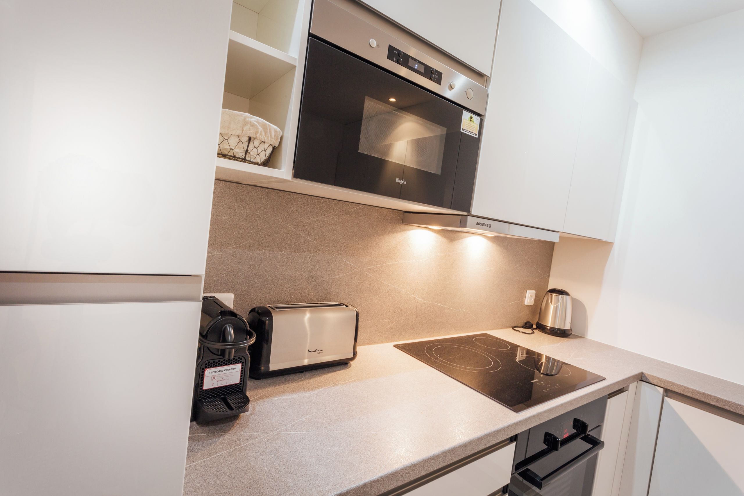 Een moderne keuken met een inbouwoven, een broodrooster, een waterkoker en een kookplaat.