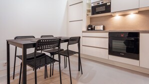 A modern kitchen with a dining table and chairs, a Bosch oven, and white cabinetry. - Luxury 1BR steps away from Champs Elysees (Paris)