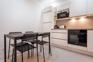 Una cocina moderna con una mesa de comedor y sillas, un horno Bosch y armarios blancos.