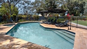 Une piscine avec des chaises longues et un parasol.