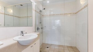 Une salle de bain avec un lavabo blanc, un miroir et une douche.