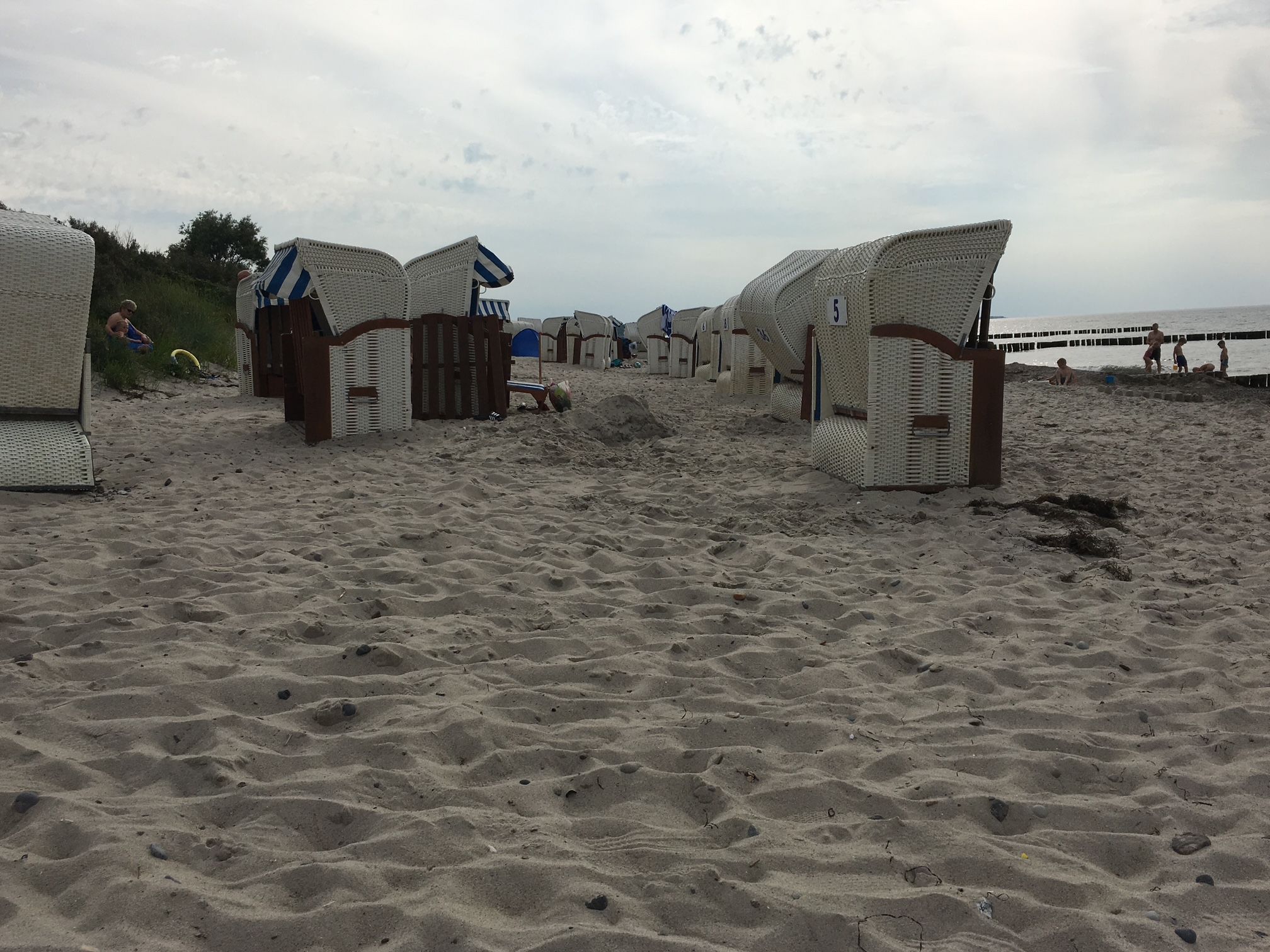 En strand med flere strandhuse og et træhegn.