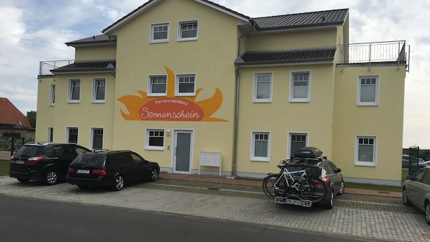 A two-story building with a yellow facade, multiple windows, and a sign indicating a restaurant. - Comfortable "Lachmöwe" vacation apartment, 62 square meters, with a large terrace featuring a beach chair and a parking space (Börgerende-Rethwisch)