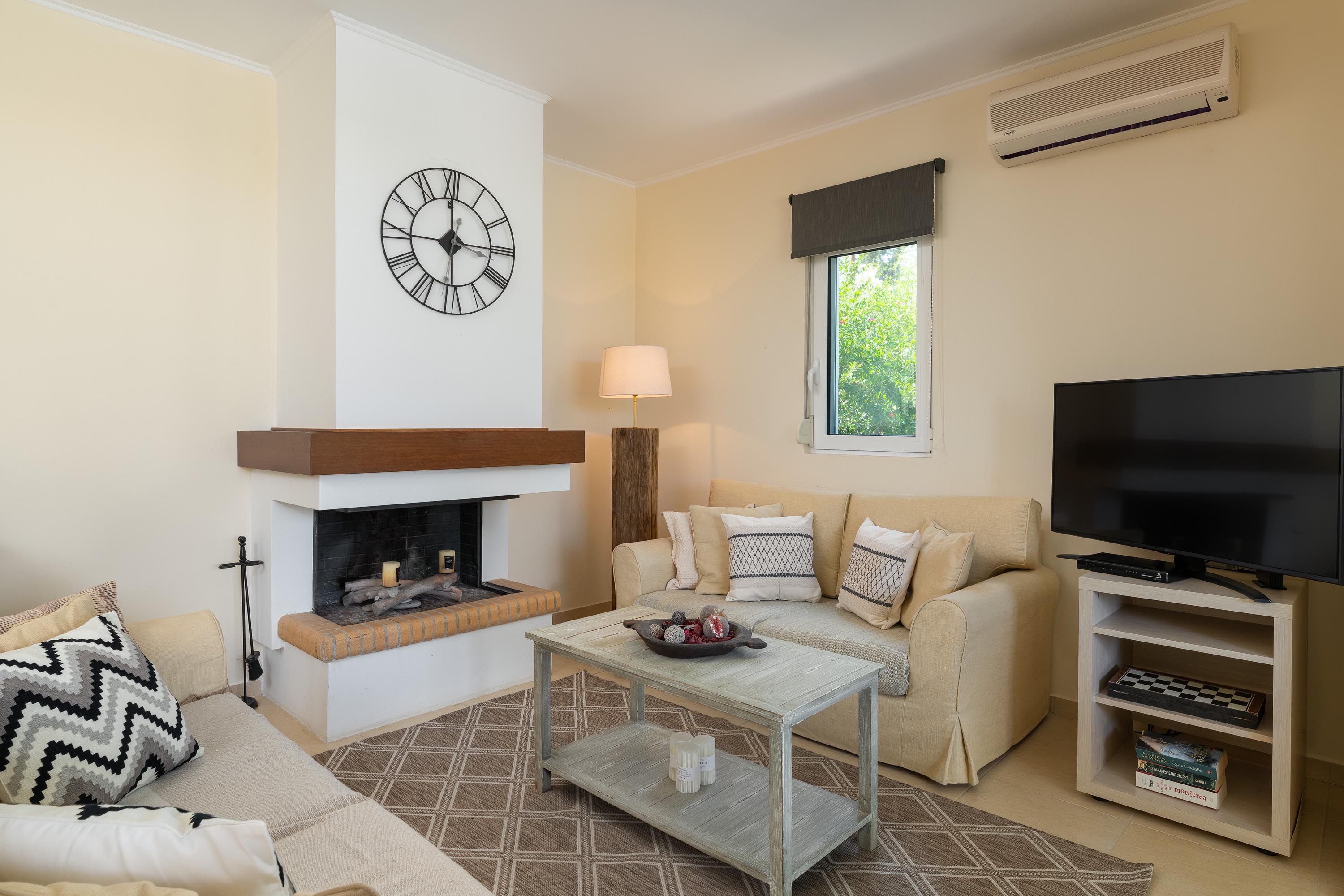 A living room with a fireplace, sofa, television, and a bookshelf.