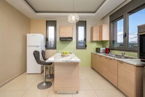 Eine moderne Küche mit einer Marmorinsel, Holzschränken, einem Einbauofen und Blick durch die Fenster.