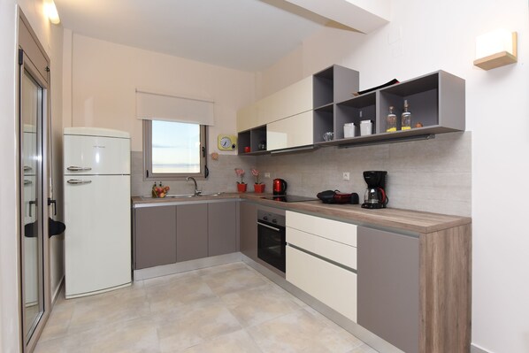A modern kitchen with a built-in refrigerator, a coffee maker, and a kettle on the countertop. - Mon Emvasia Margarites Villa B (Mylopotamos)